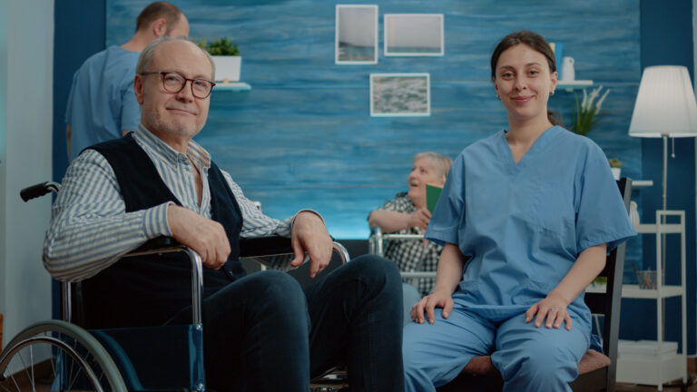Portrait of disabled senior man sitting with woman nurse